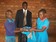Antony  ogembo hands over  adonation  of  used   uniforms  to  a  fellow  pupil who  is  an  orphan  in  the  initiative  of  children  for  chidren  in  schools as  the  founder  of  one  world  childcare  looks  on.